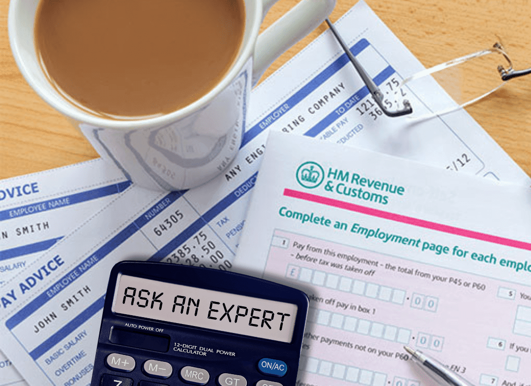 A workspace with tax forms, a calculator with the text 'ASK AN EXPERT', a cup of coffee, eyeglasses, and a pen.